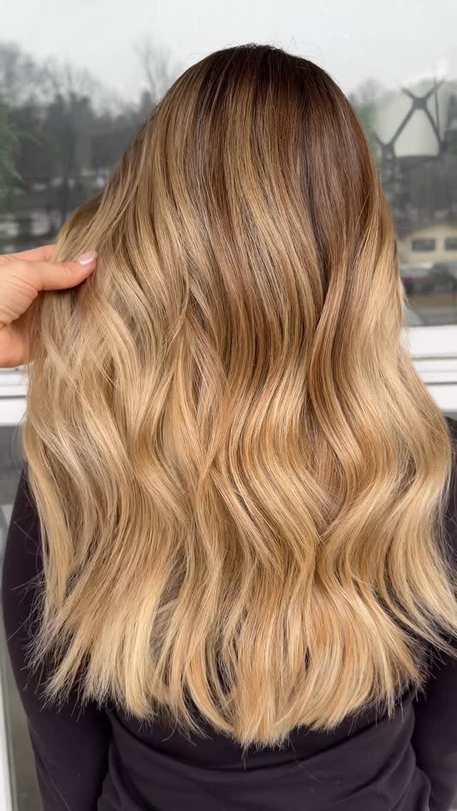 Wavy hair fades from dark brown roots to golden blonde ends