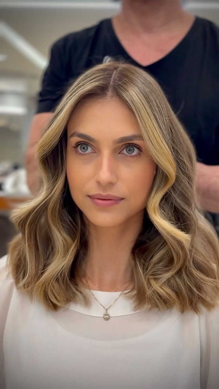 Woman with subtle golden balayage through long medium brown hair in a salon