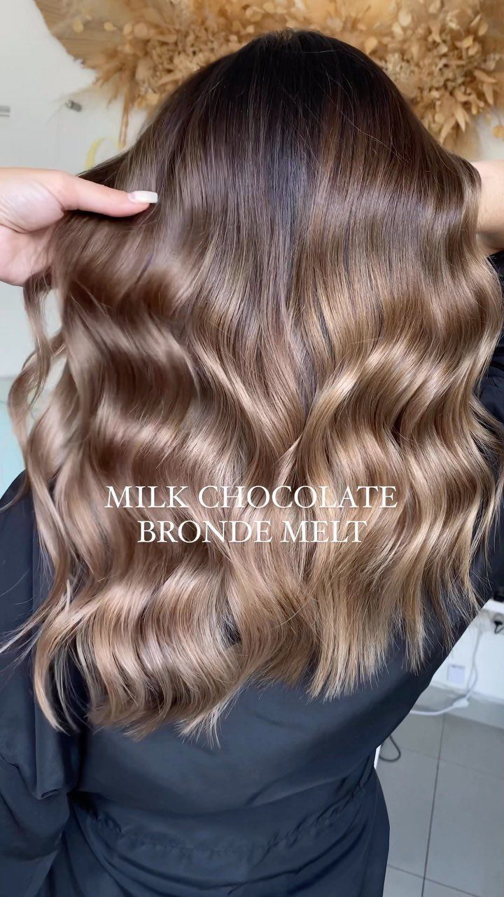 Wavy brown hair with caramel highlights and dark roots, shown from behind