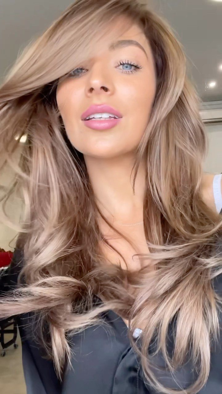Woman with long wavy brown hair and muted blonde highlights