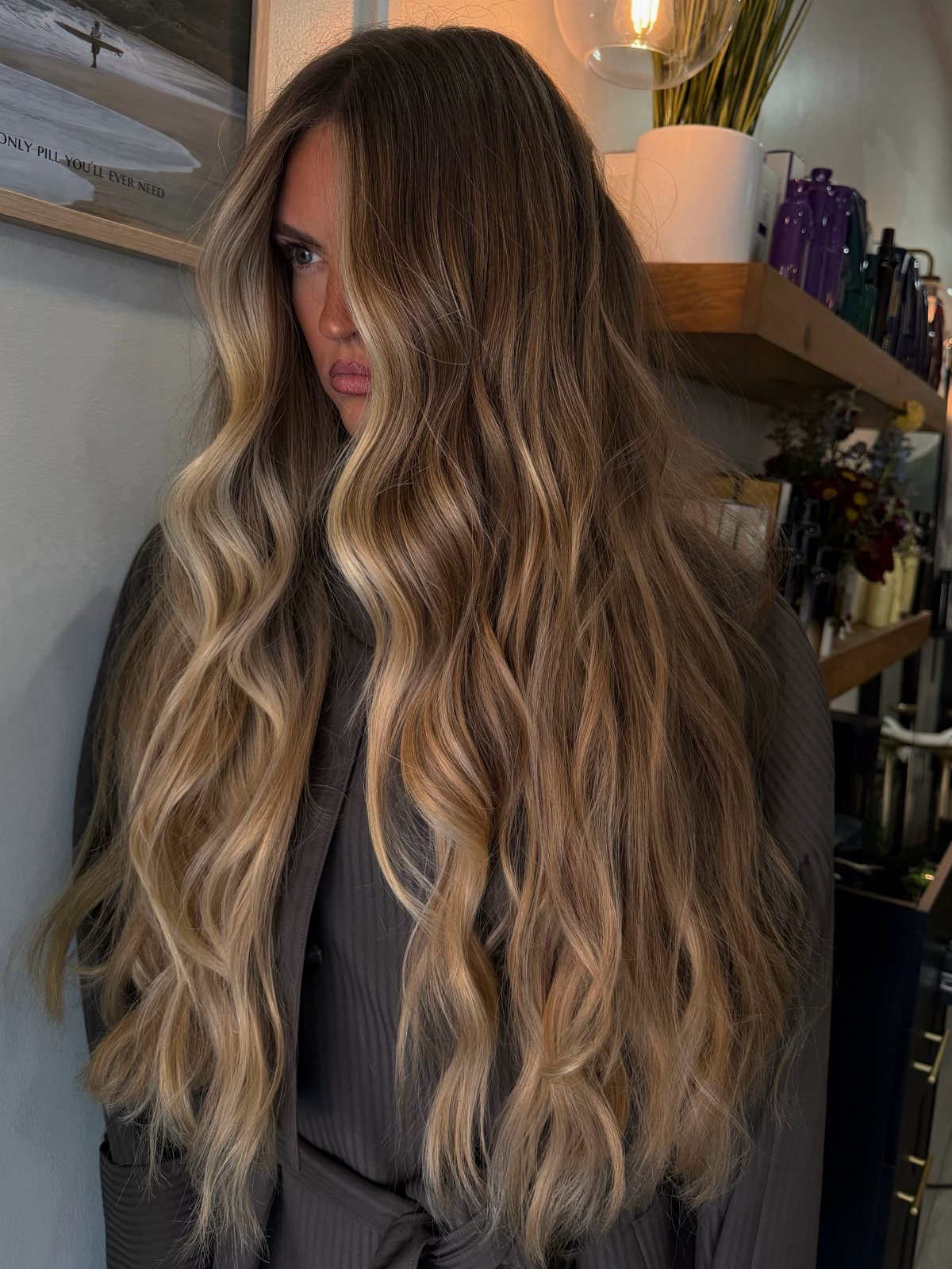Woman with long wavy brown hair and warm wheat-blonde highlights