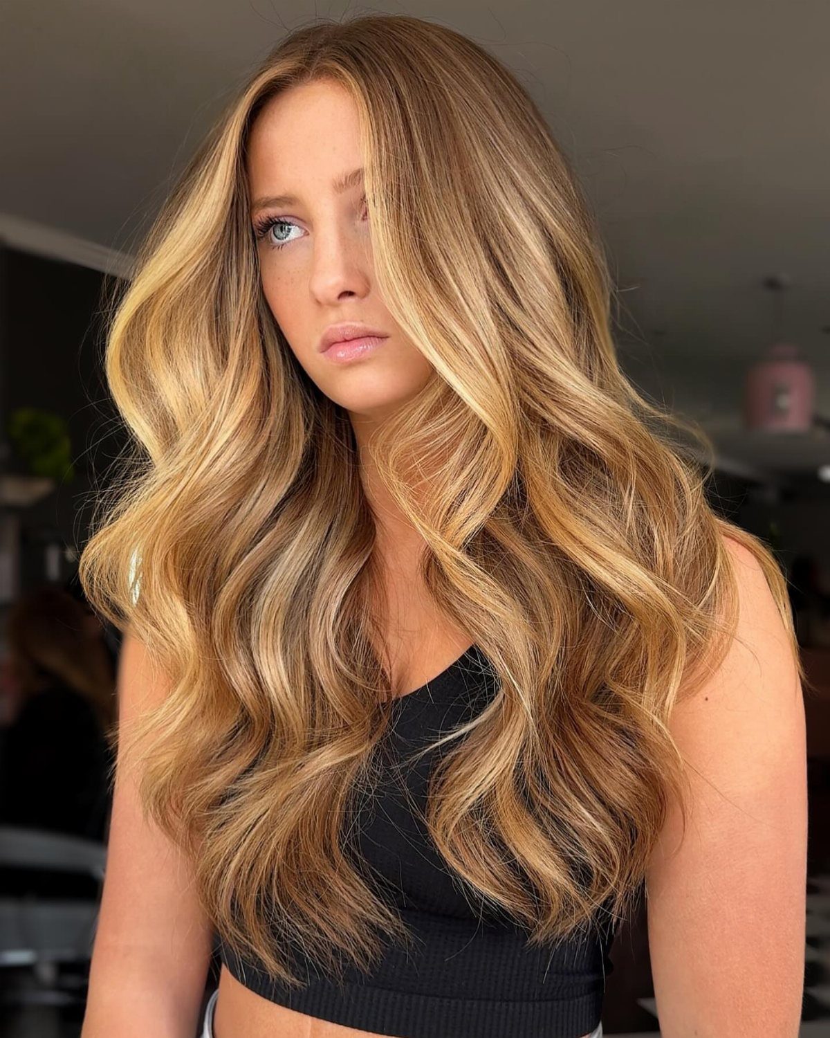 Woman with long blonde balayage waves and darker roots