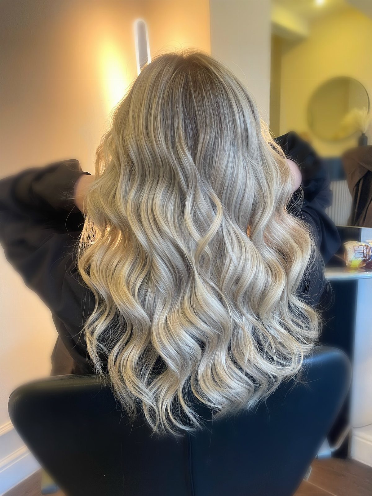 Long platinum-streaked blonde hair styled in loose waves in a salon