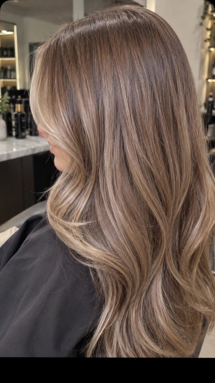Long bronde hair with beige-blonde highlights styled in loose curls at a salon