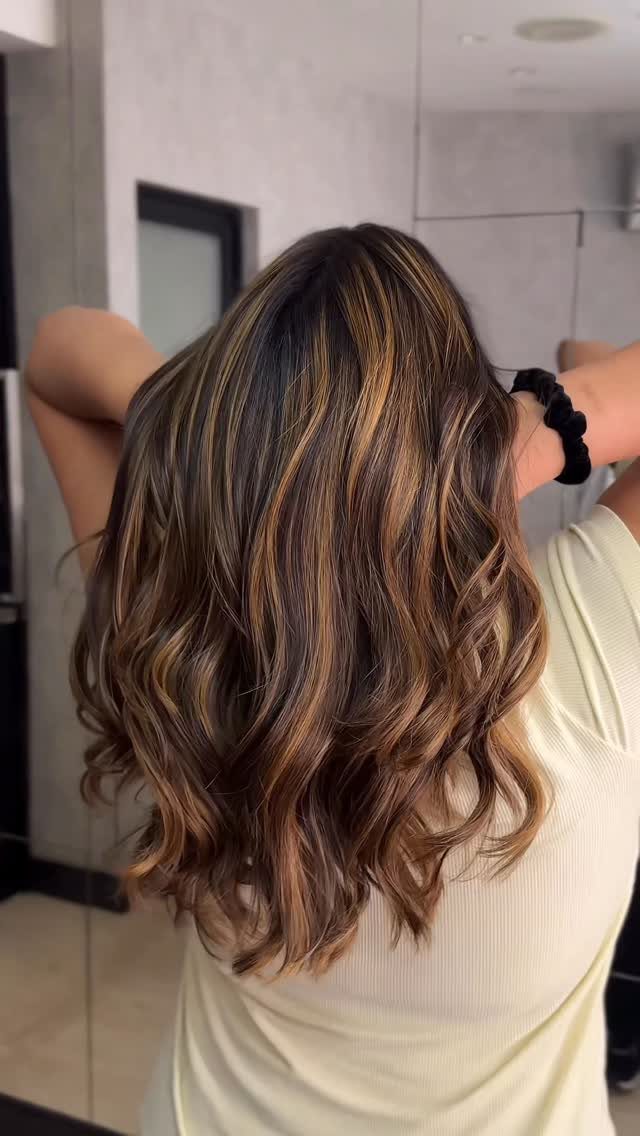 Long dark waves with warm caramel and honey-blonde highlights