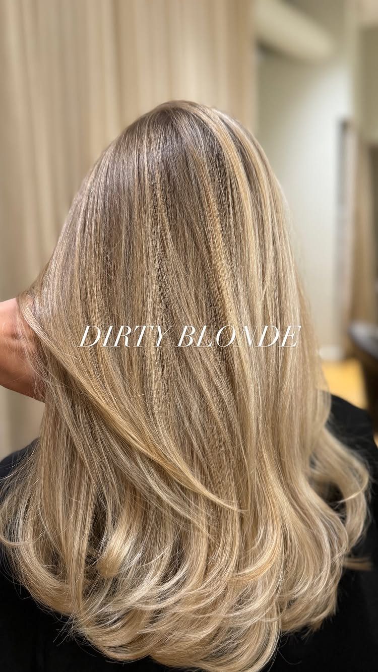 Layered dirty blonde hair with darker roots and soft, wavy highlighted ends