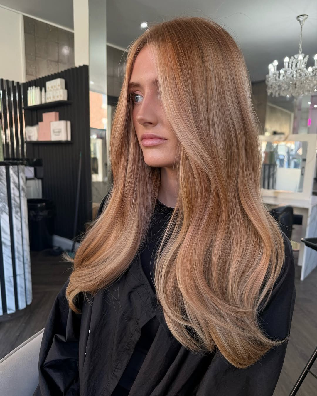 Woman with long, smooth strawberry blonde hair seated in a salon