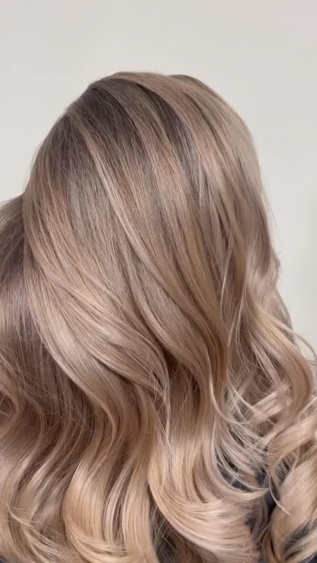 Beige-blonde hair with darker roots and soft waves against a light gray background