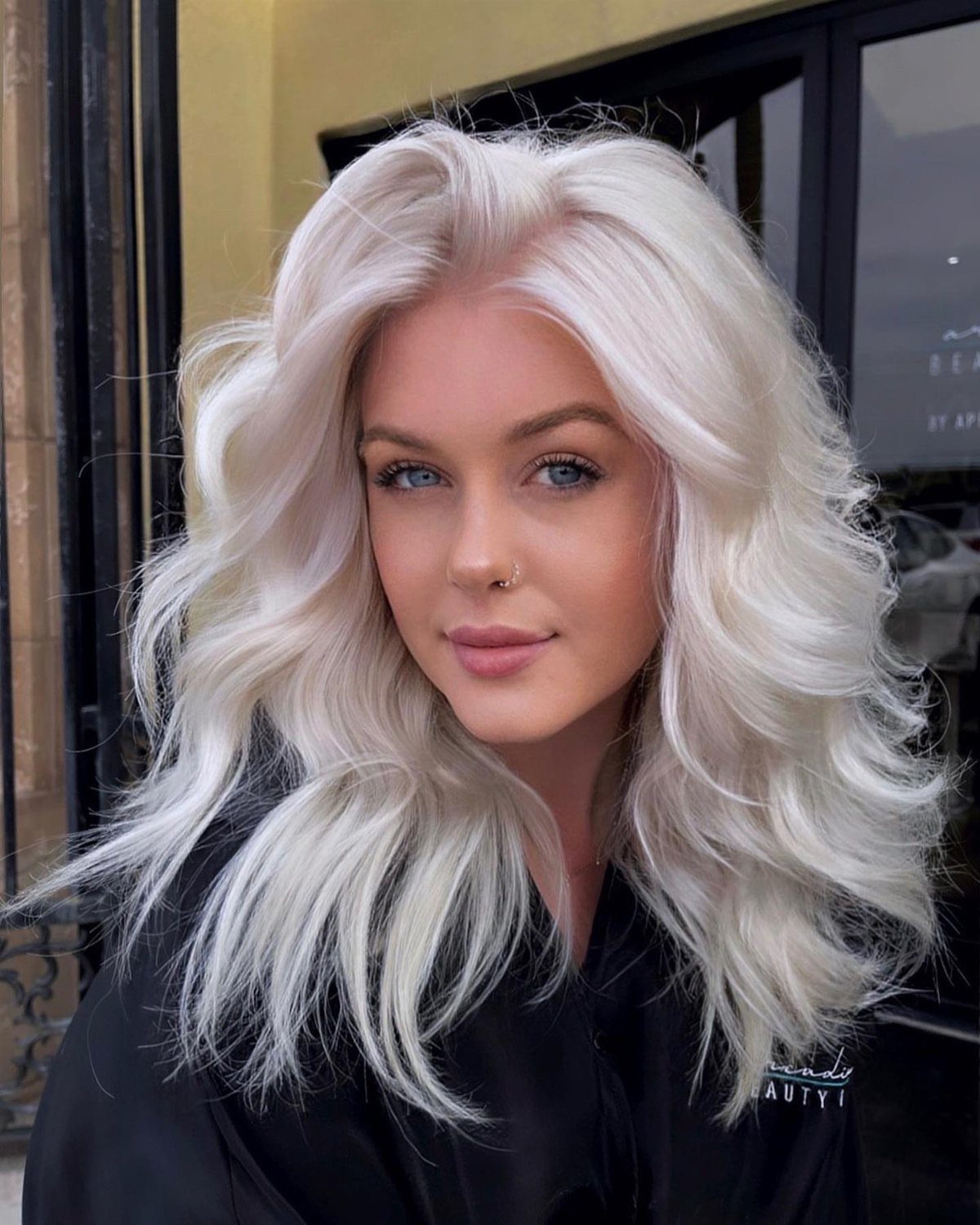 Platinum blonde hair styled in long, voluminous waves around a person's face
