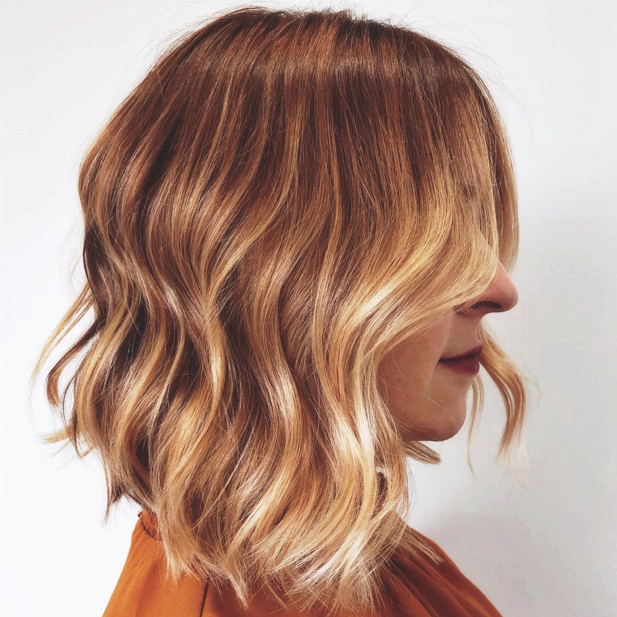 Wavy brown hair with golden and copper highlights shown in side profile