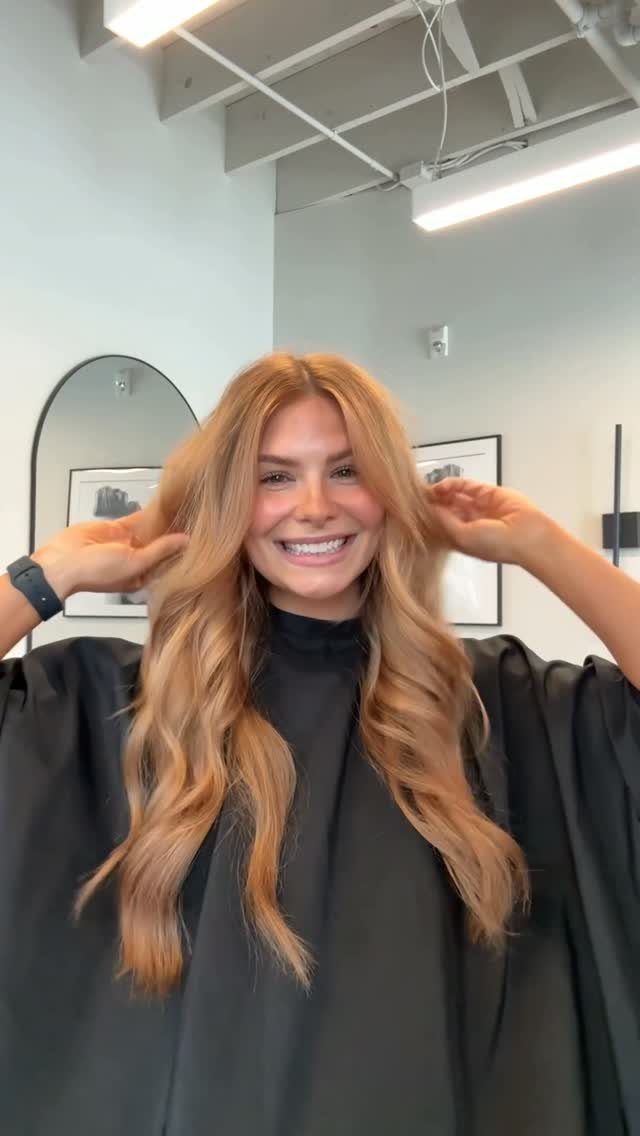 Woman displaying long, wavy copper-blonde hair in a salon