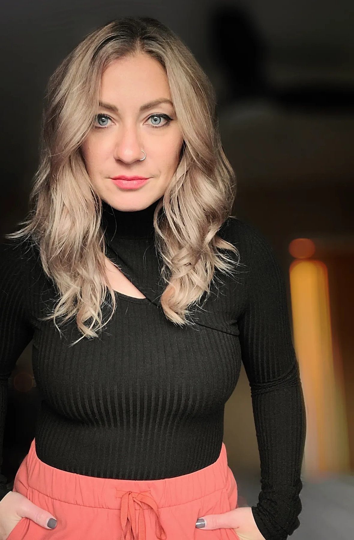 Woman showing lived-in blonde waves with darker roots and lighter highlights