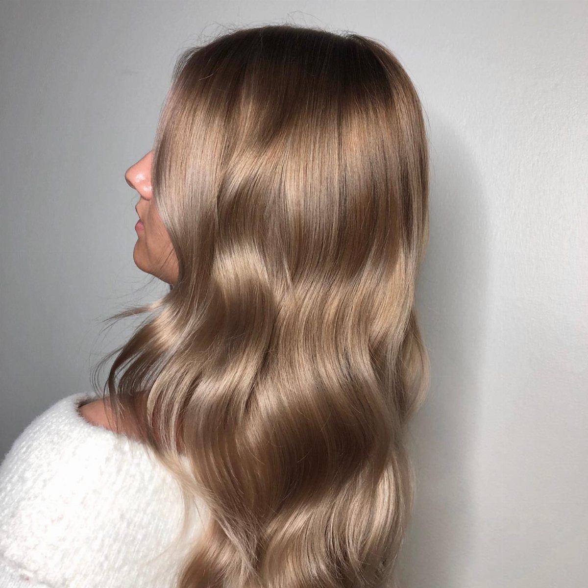 Long wavy mushroom blonde hair with dark roots and cool taupe tones