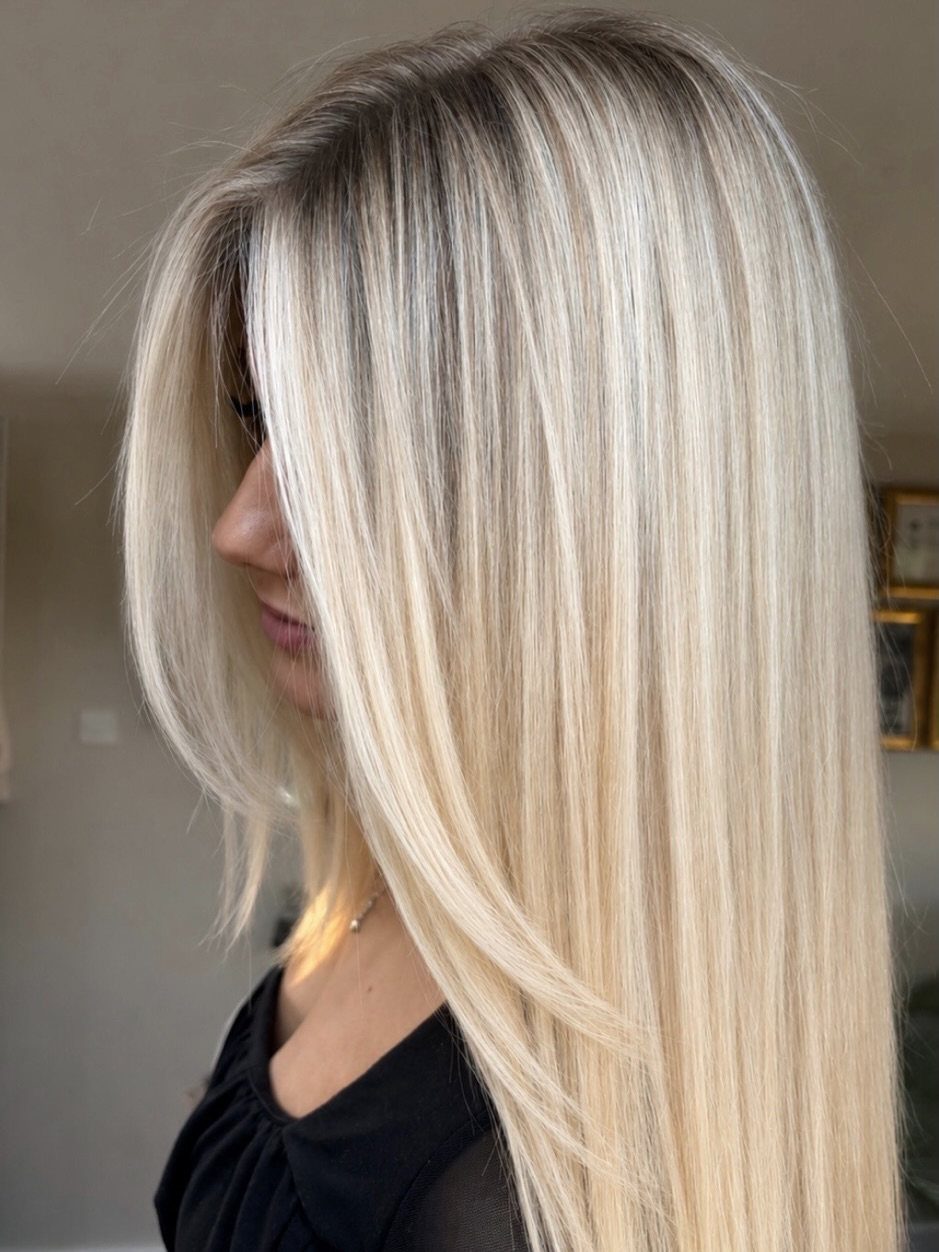 Long pale blonde hair with bright frosted strands falls straight past a black top