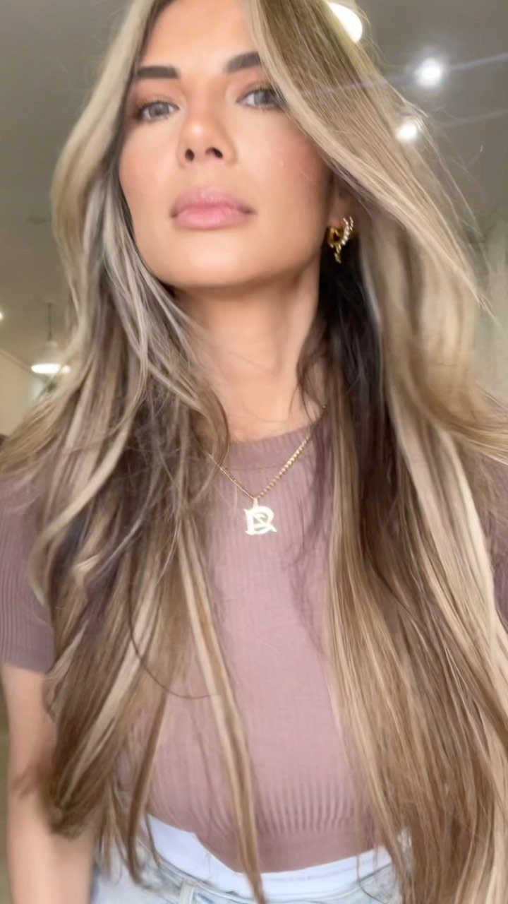 Woman with long blonde hair showing soft brown roots and lighter ends
