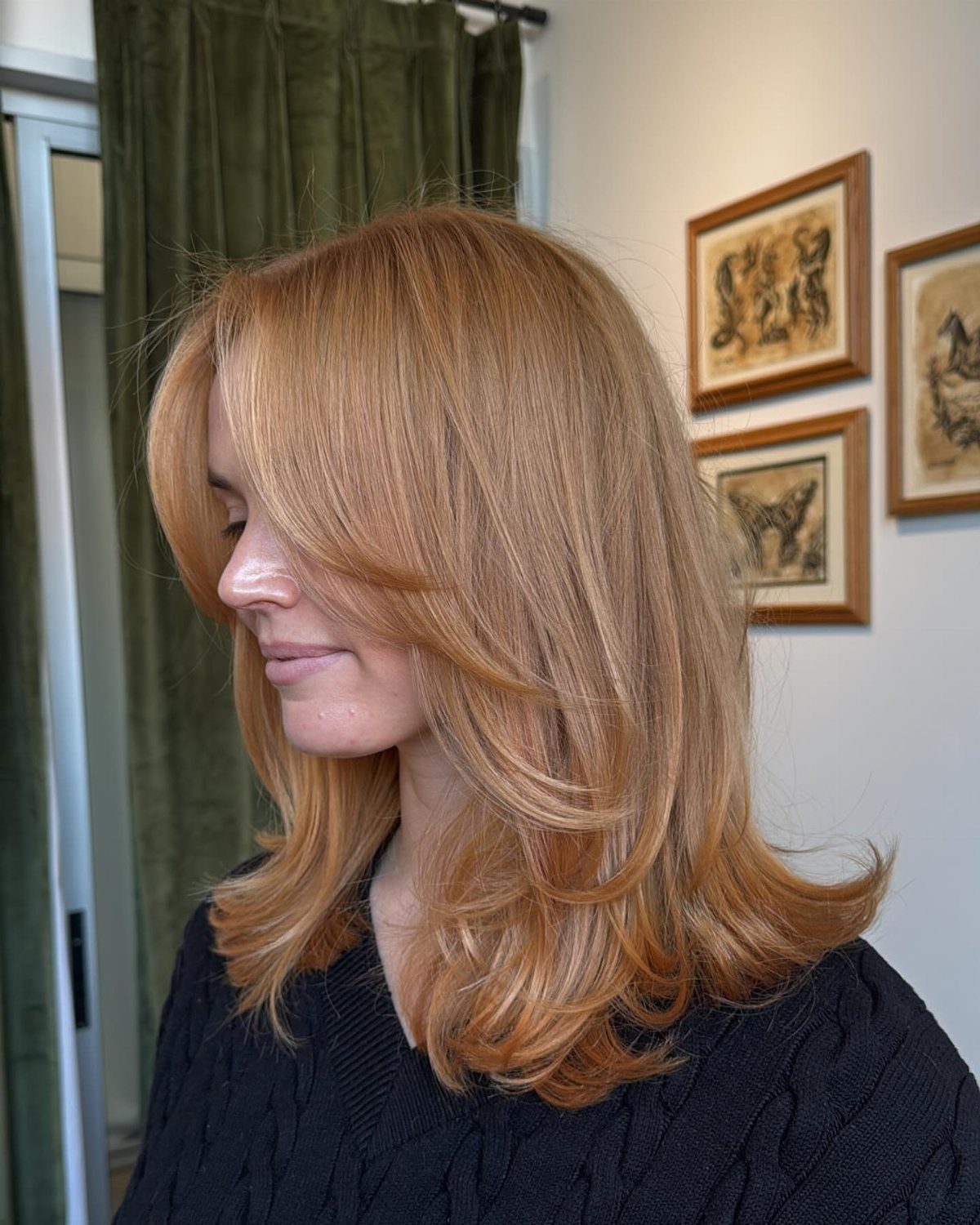 Woman with long, layered copper-blonde hair in an indoor portrait