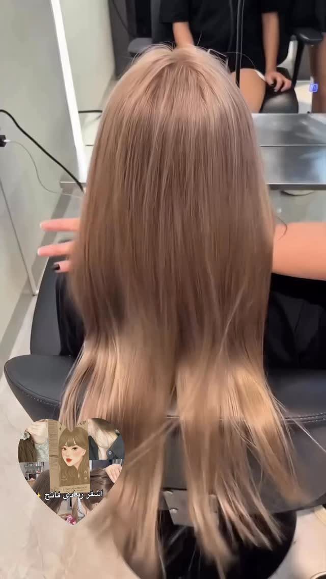 Long pale ash-blonde hair hangs straight down the back in a salon