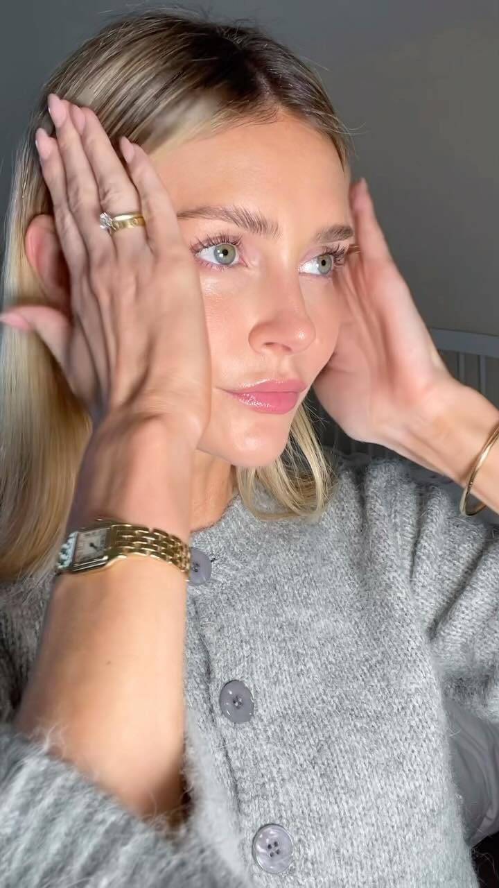 Woman with medium blonde hair holds her hands beside her face