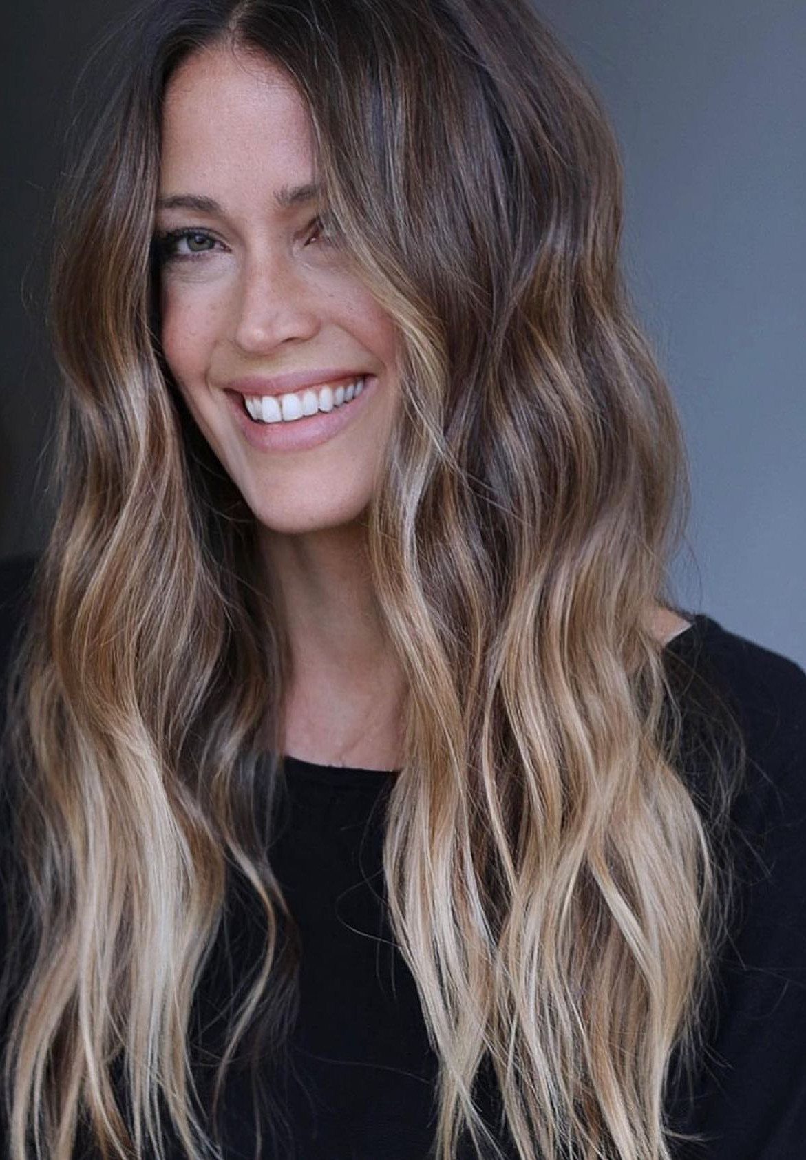 Long wavy mushroom blonde hair with dark roots and cool sandy highlights