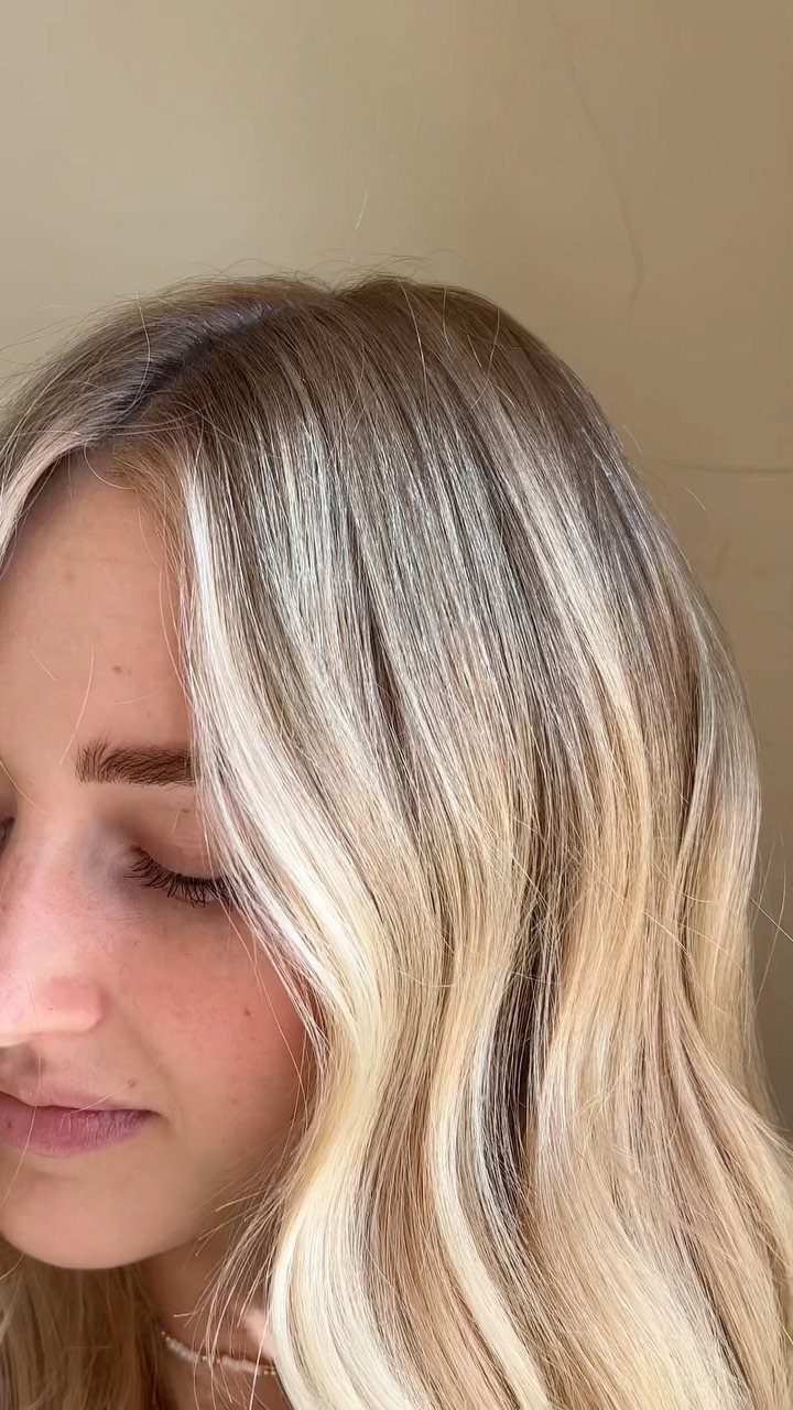 Long blonde hair with darker roots and soft, cool-toned highlights