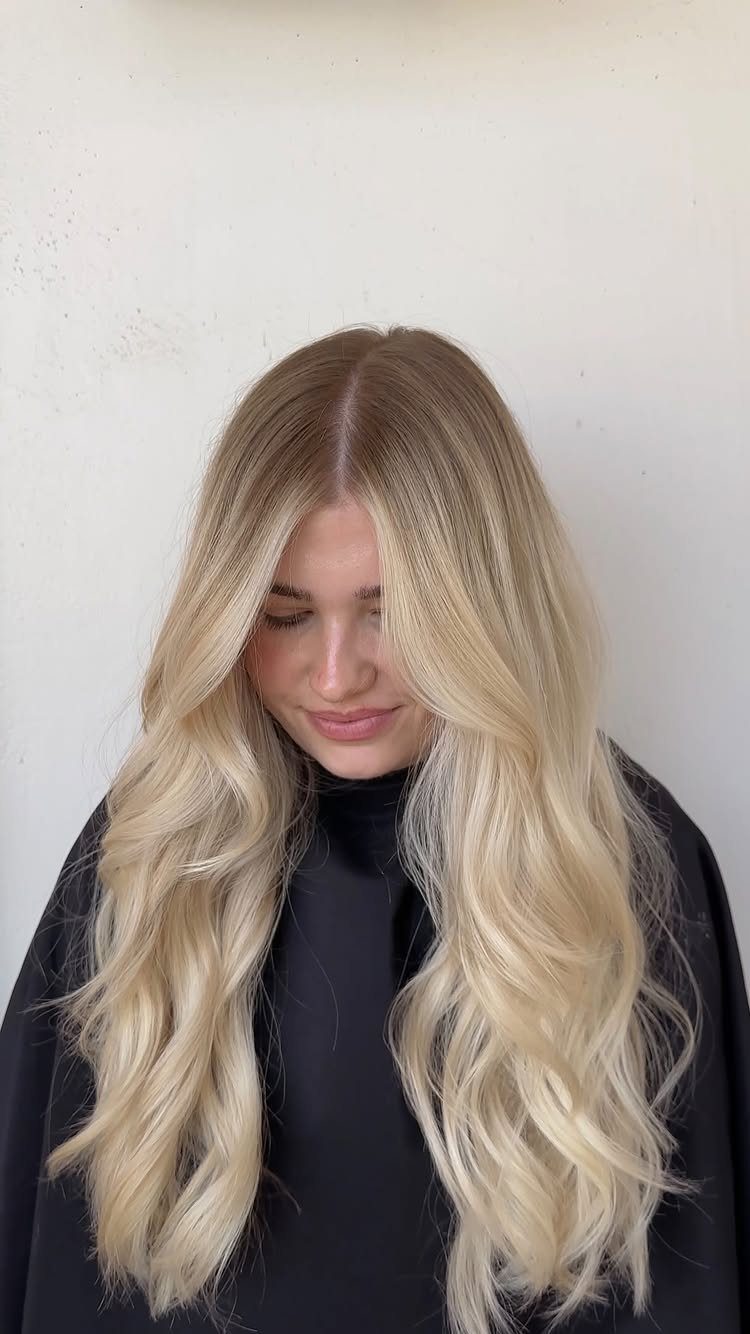 Long wavy blonde hair with soft brown roots and pale, creamy ends