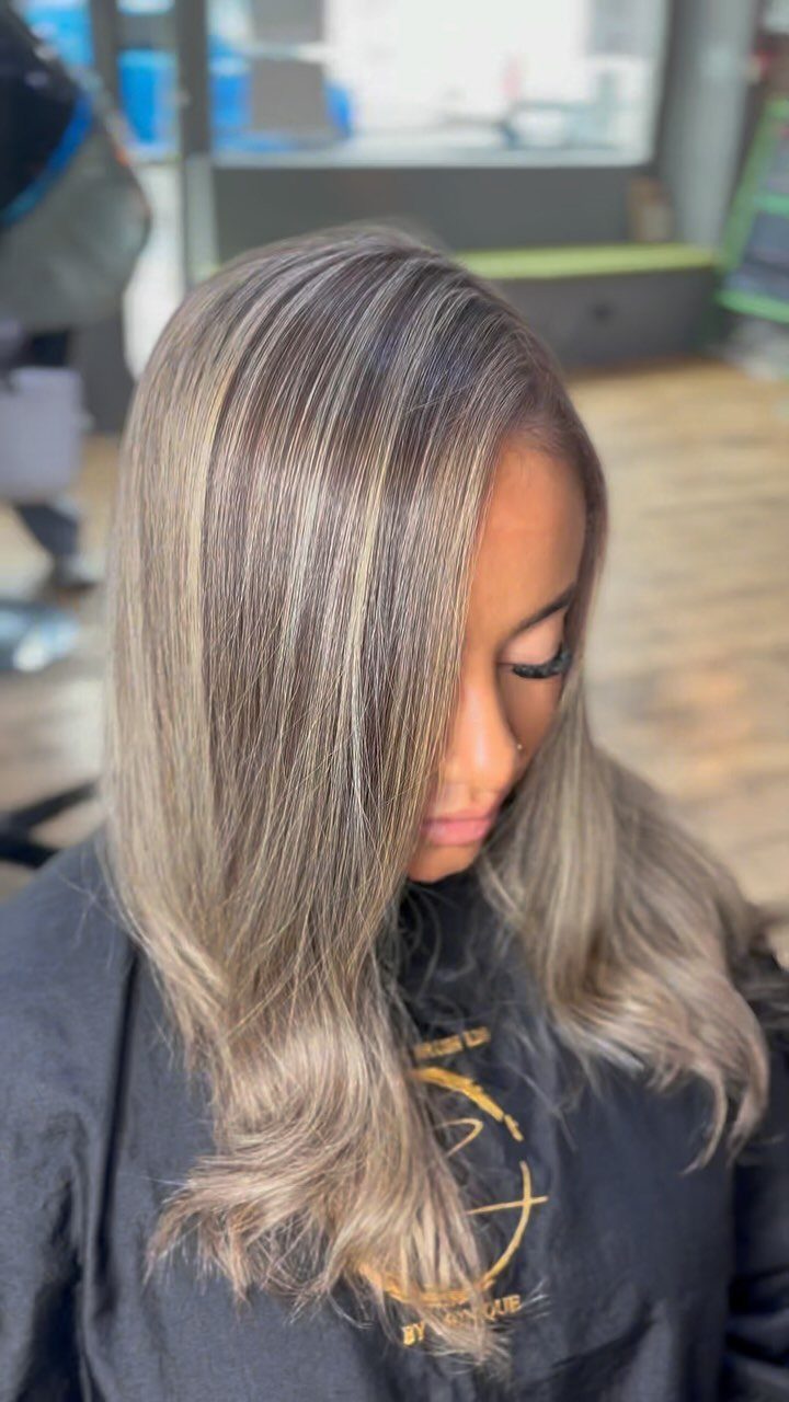 Woman showing long brown hair with cool ash-blonde highlights in a salon