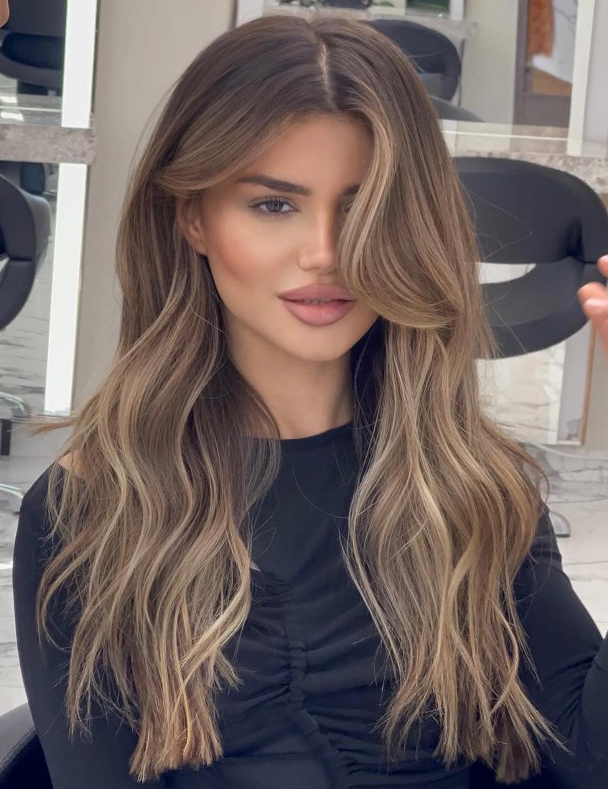 Woman with long brown hair and soft caramel-blonde face-framing highlights