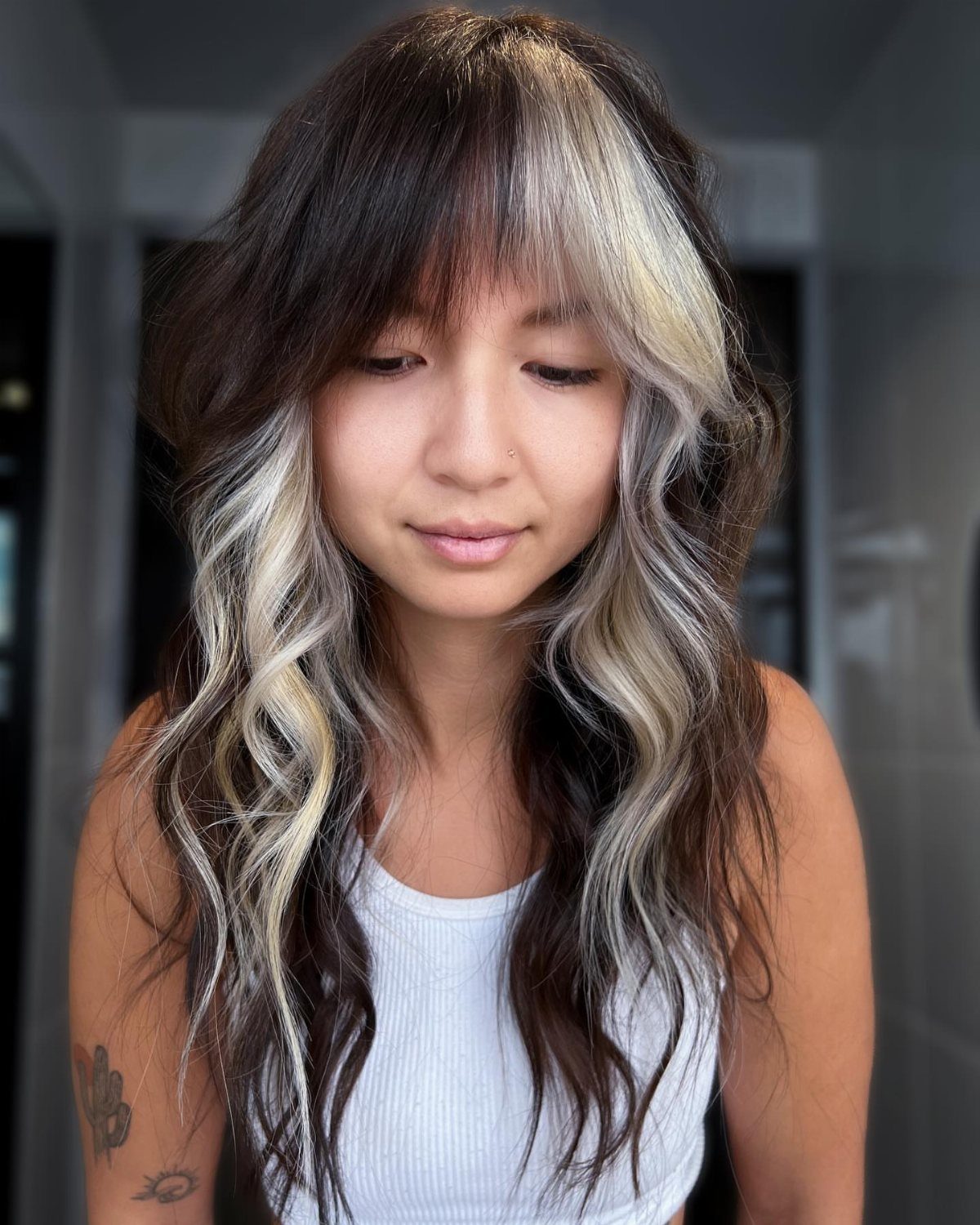 Woman showing long brown hair with a bold, chunky blonde face-framing section