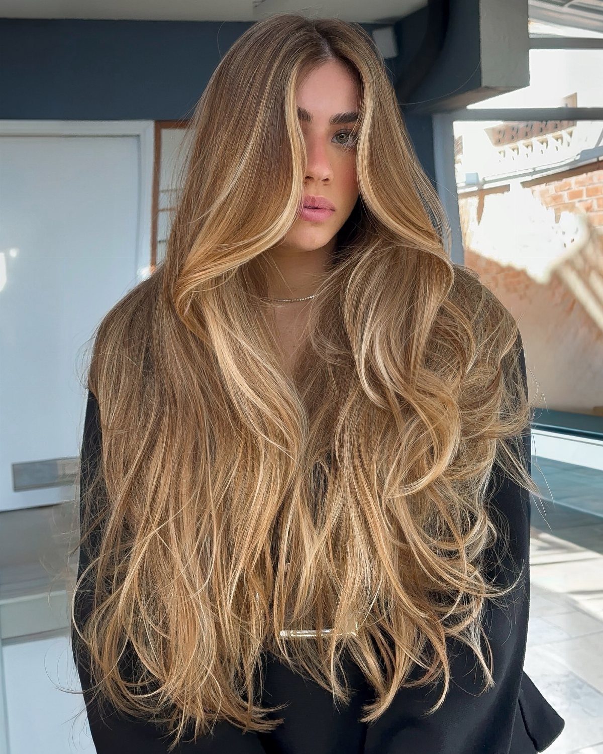 Long brown hair melts through caramel tones into flowing blonde waves