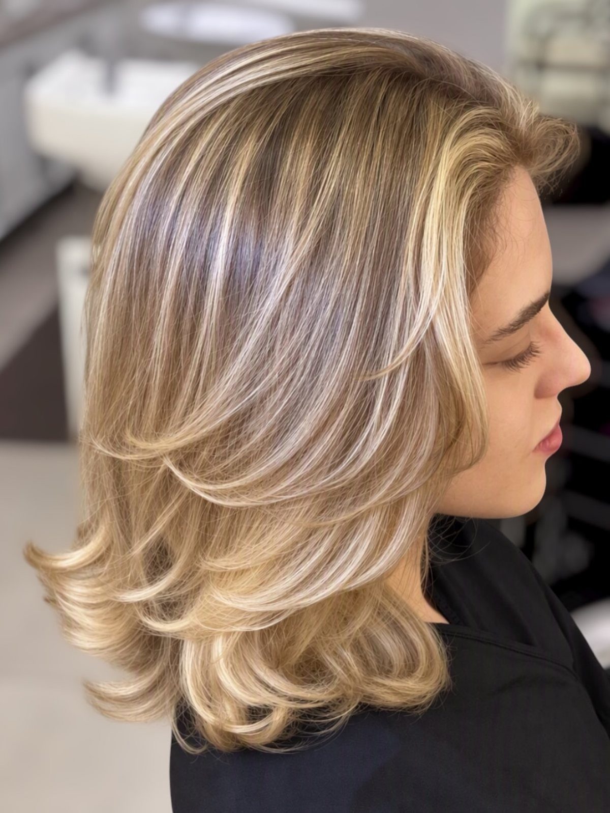 Layered light brown hair with champagne blonde highlights and curled ends