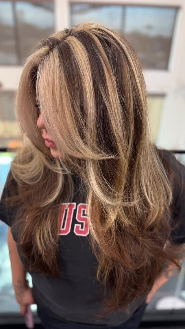 Long brown hair with broad blonde face-framing highlights and layered curls