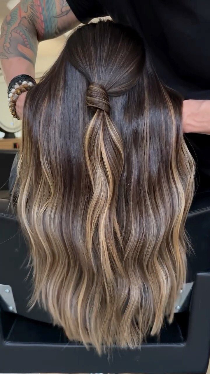 Long wavy brown hair with blended blonde highlights and a twisted crown section