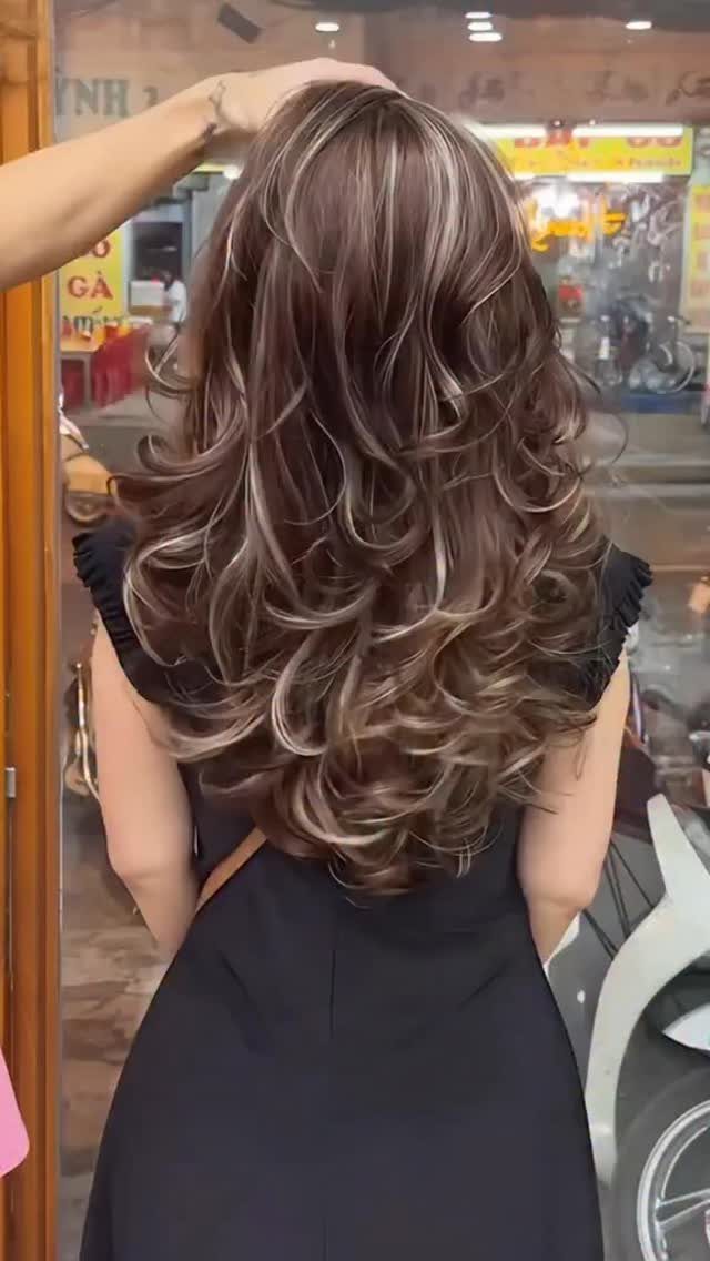 Long brunette hair with golden blonde highlights in layered curls