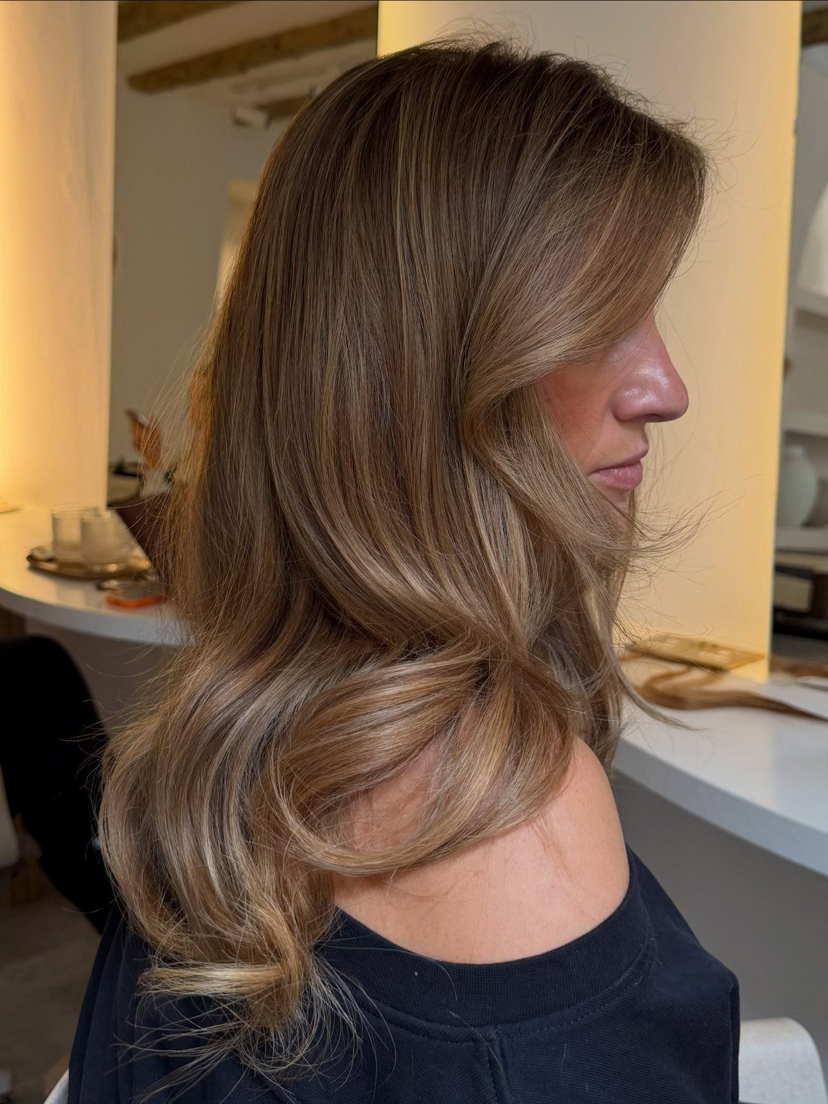 Long wavy brown hair with golden blonde tones frames a woman's profile