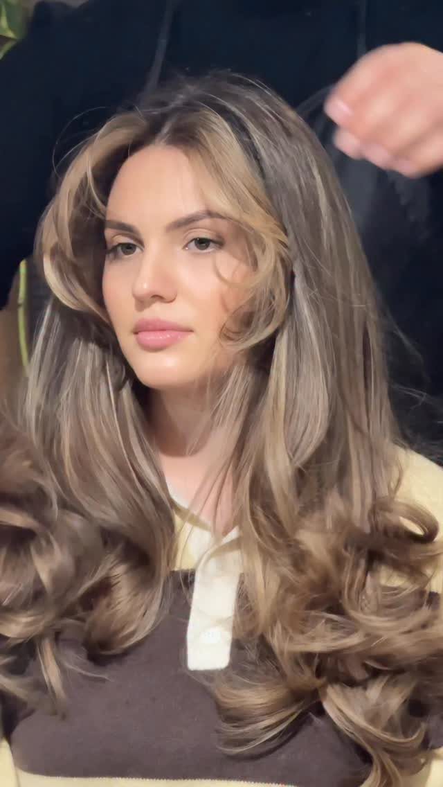 Woman with long brown hair and blended blonde highlights in loose curls