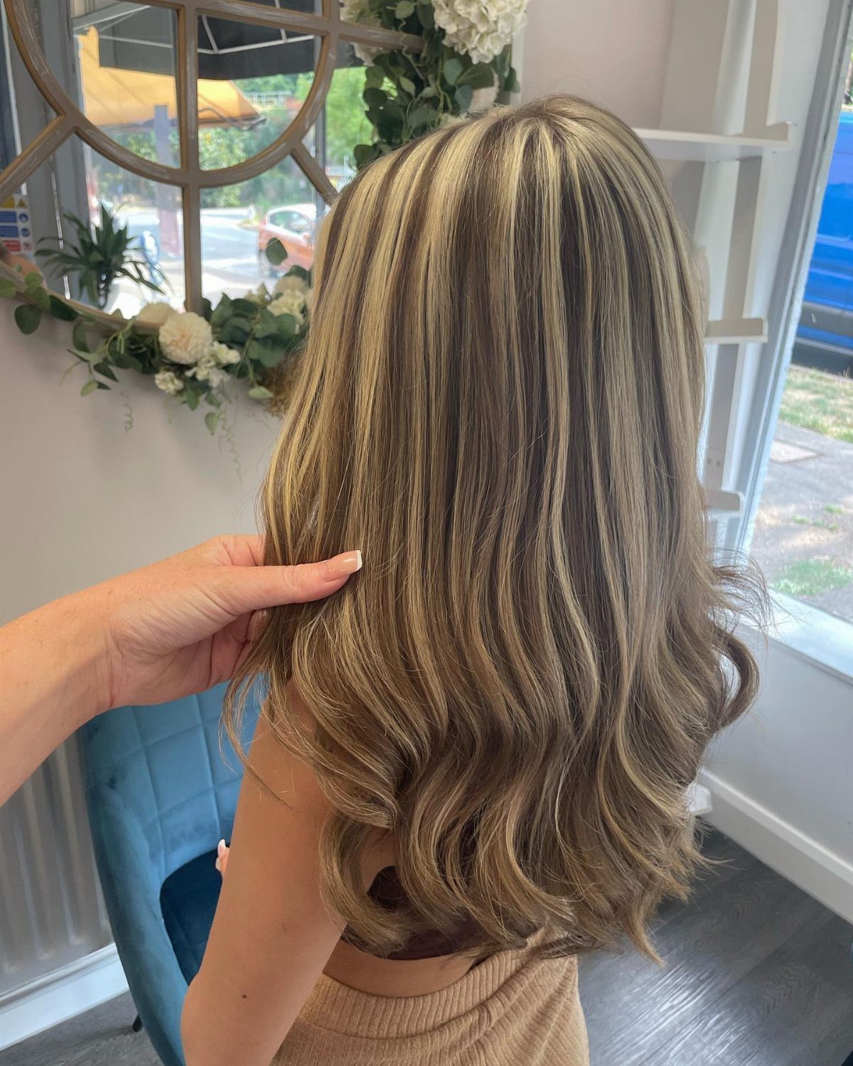 Brown hair with fine blonde highlights curled at the ends in a salon