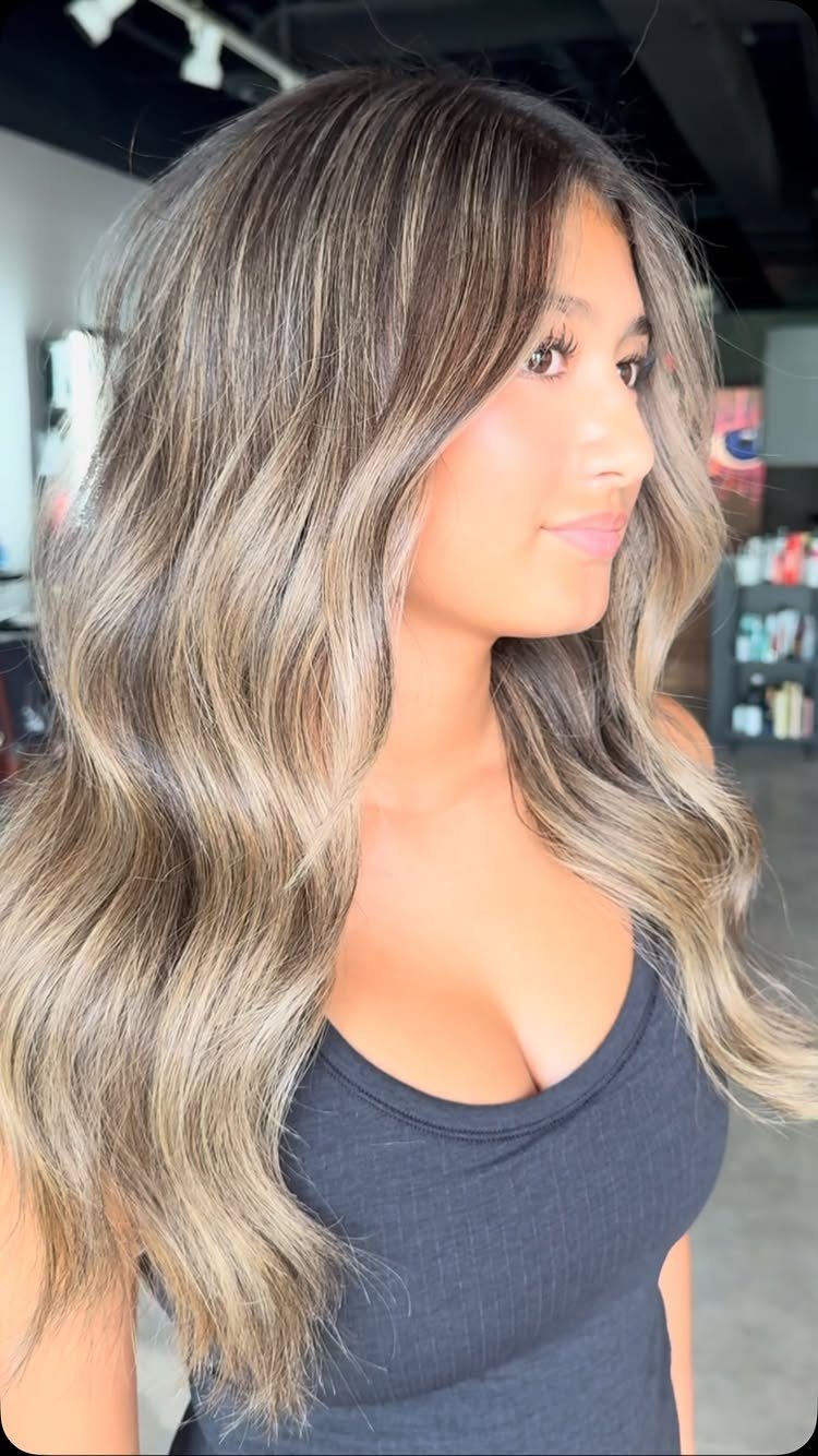 Woman with long wavy mushroom brown and blonde hair in a salon
