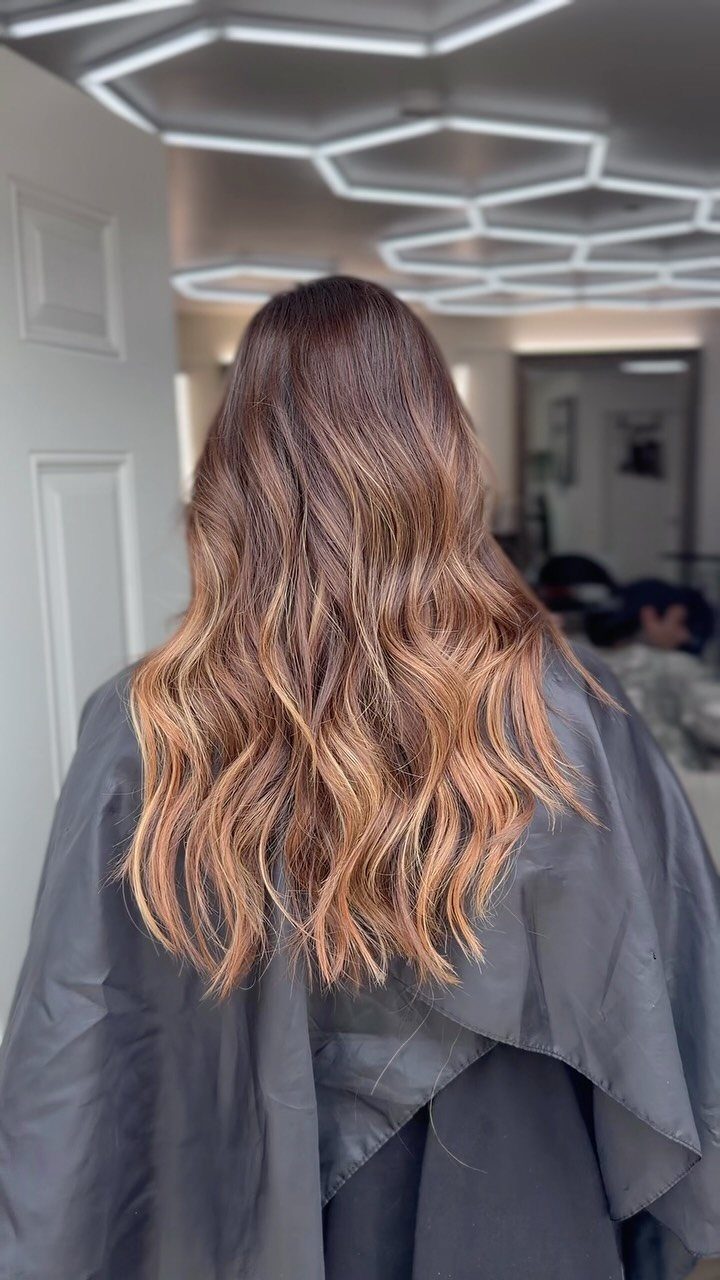 Long wavy brown hair with warm chestnut and caramel-blonde balayage