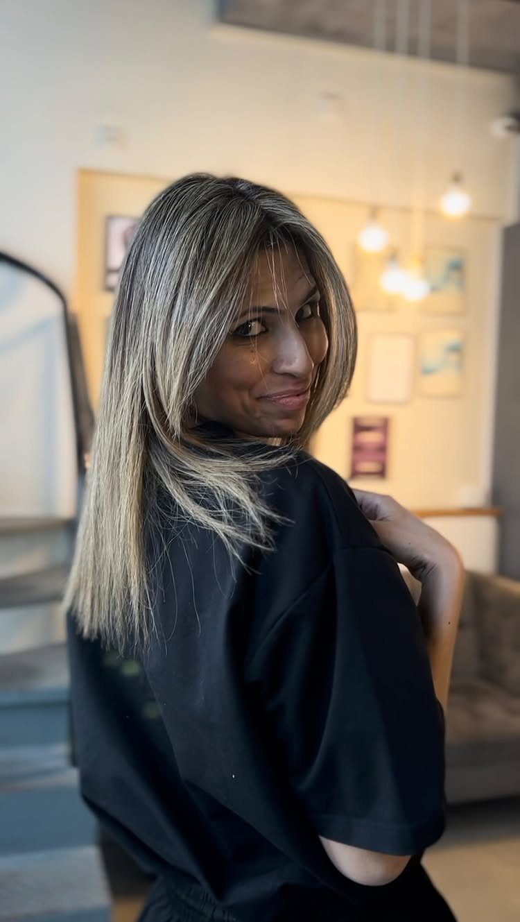 Woman showing dark hair with cool beige-blonde highlights in a salon