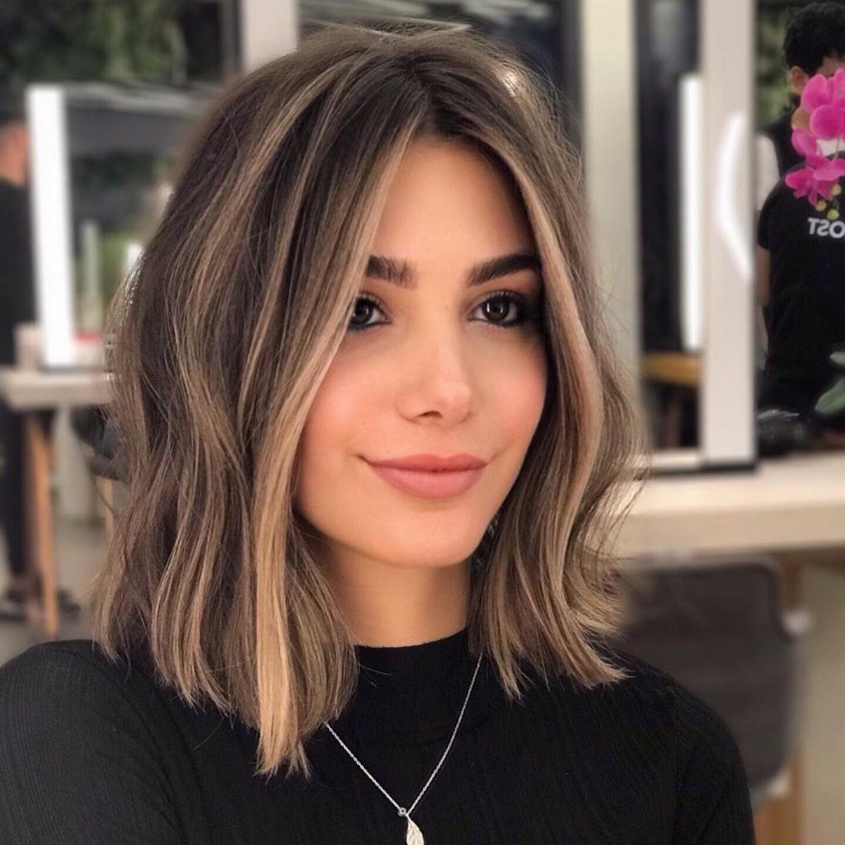 Woman showcasing shoulder-length brunette hair with caramel face-framing strands