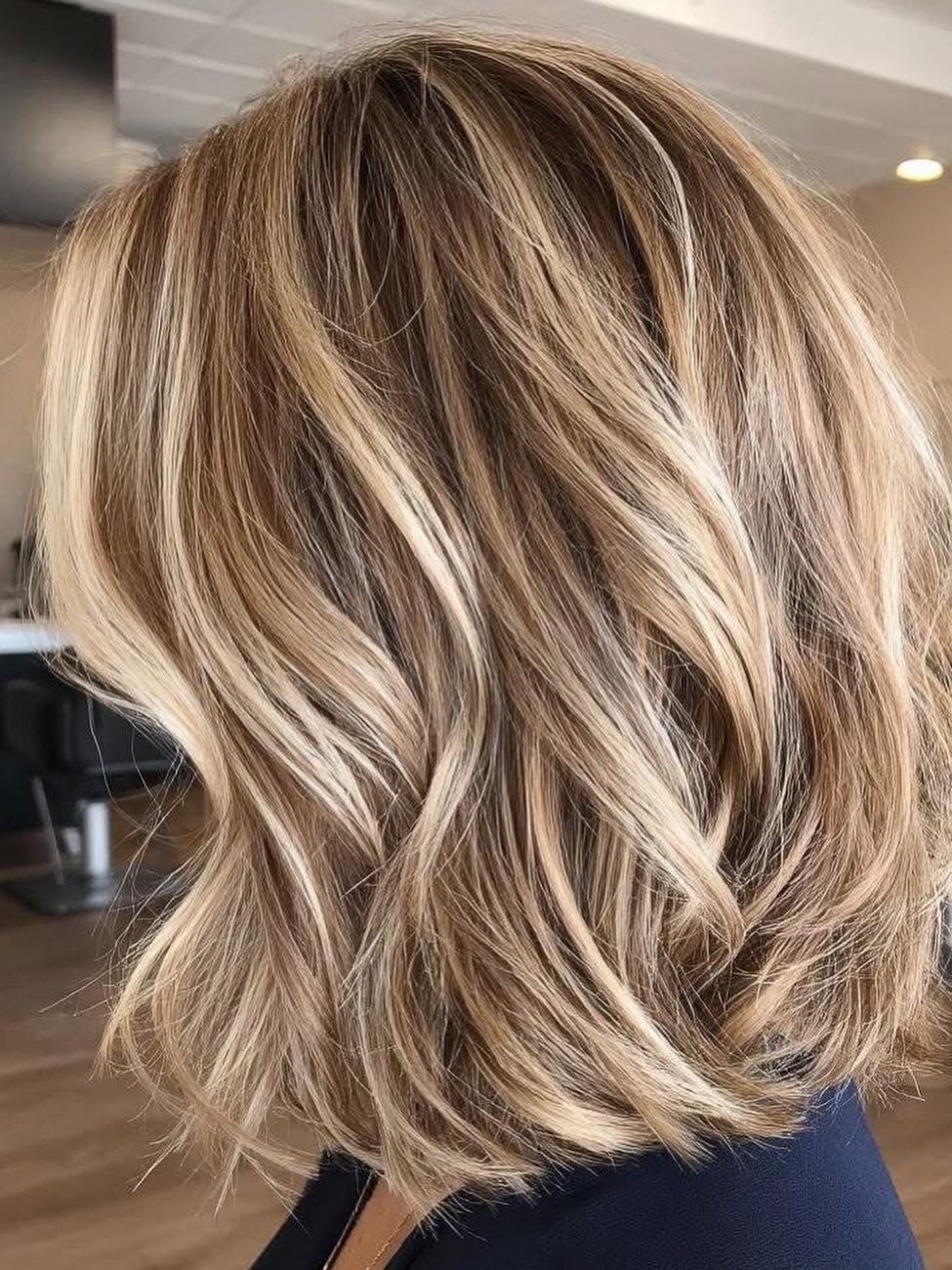 Layered blonde hair with cool beige caramel highlights in loose waves