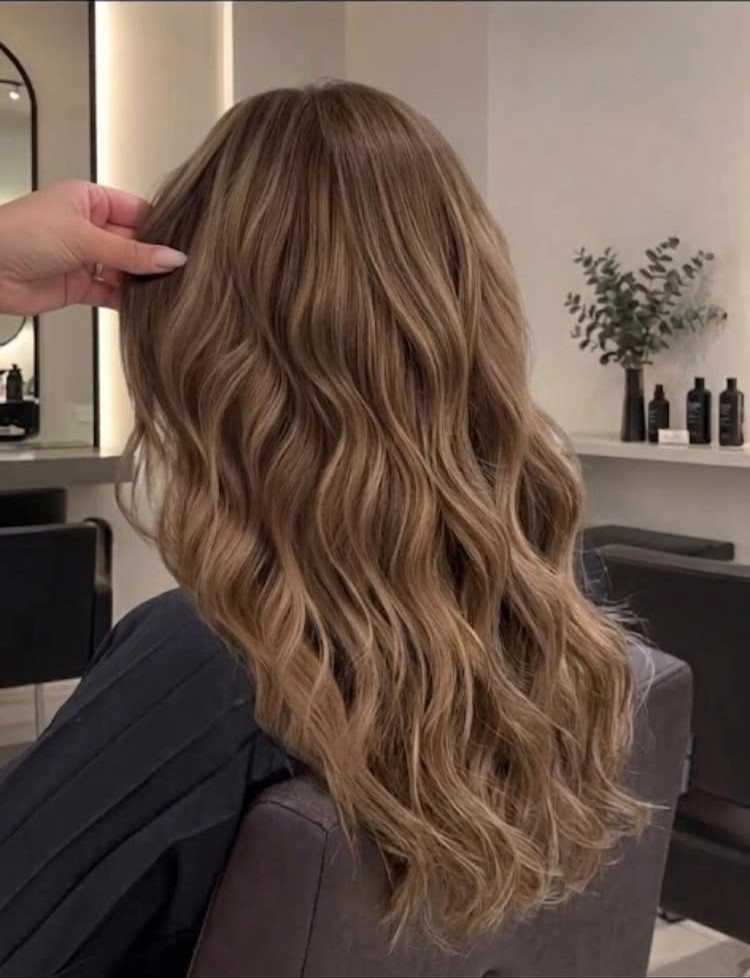Long wavy caramel blonde hair with warm highlights in a salon