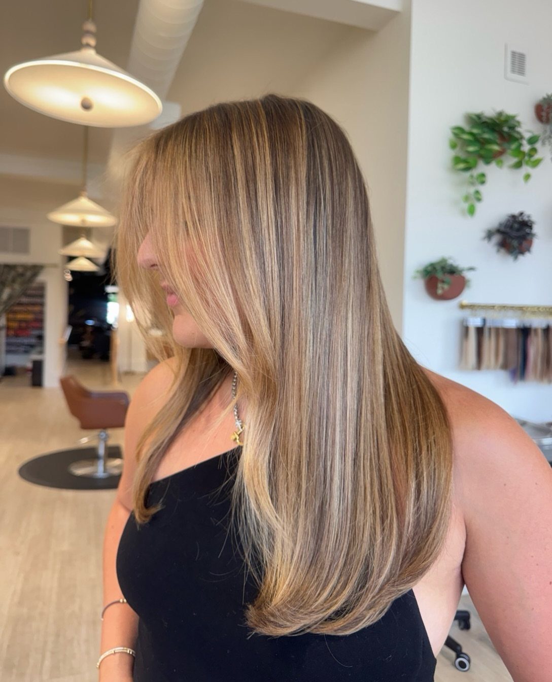 Long caramel blonde hair with lighter highlights shown in a bright salon