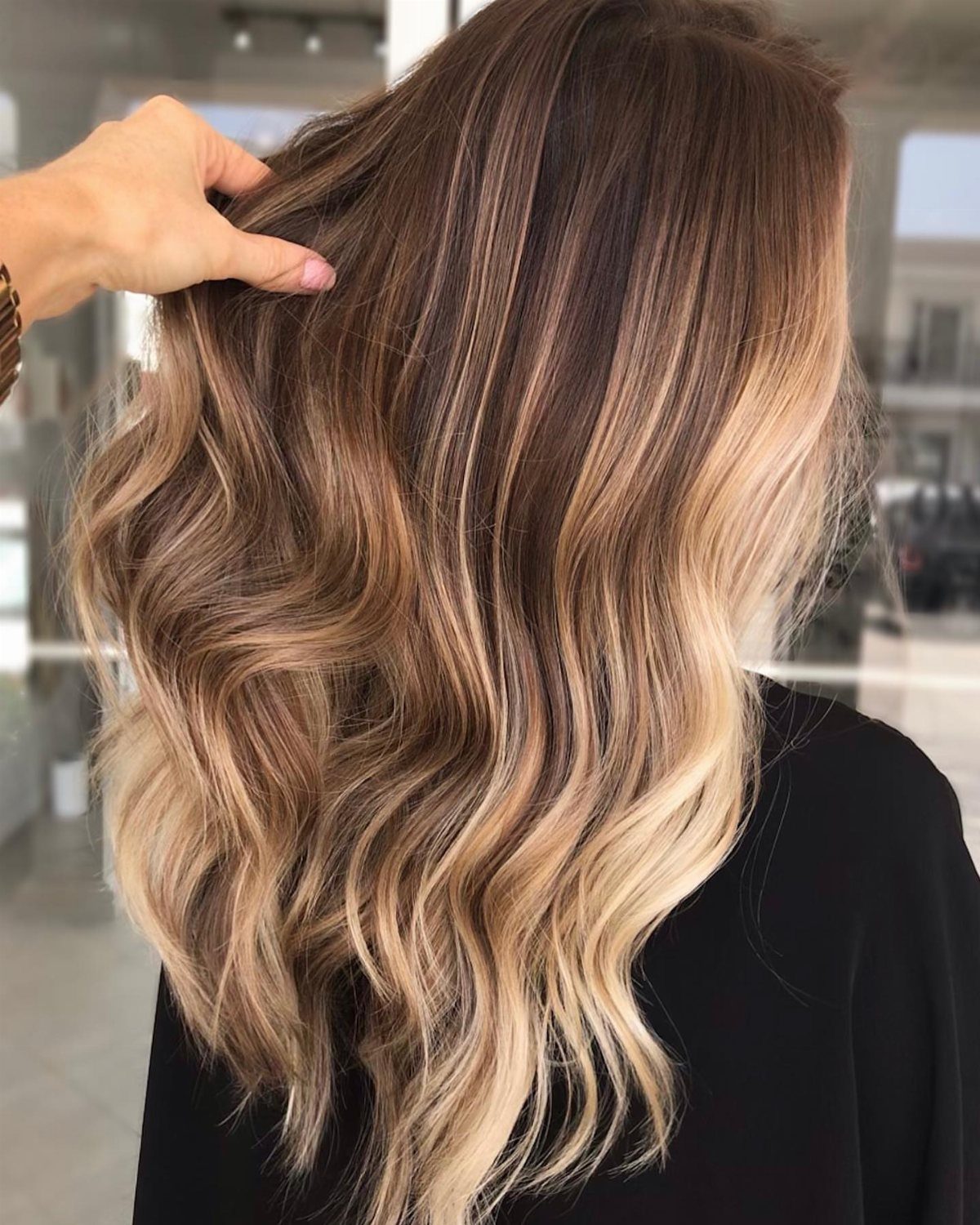 Wavy dark brown hair with blended warm caramel and blonde highlights