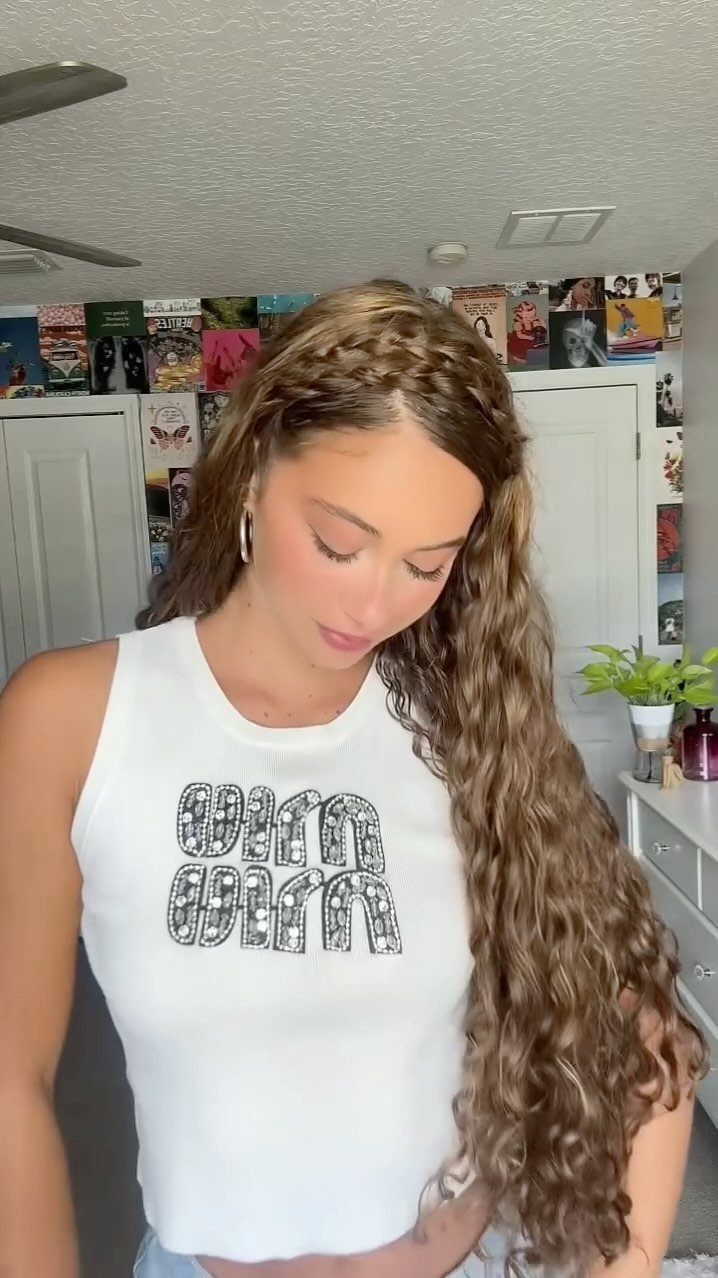 Woman with long curls wearing two braids as a headband