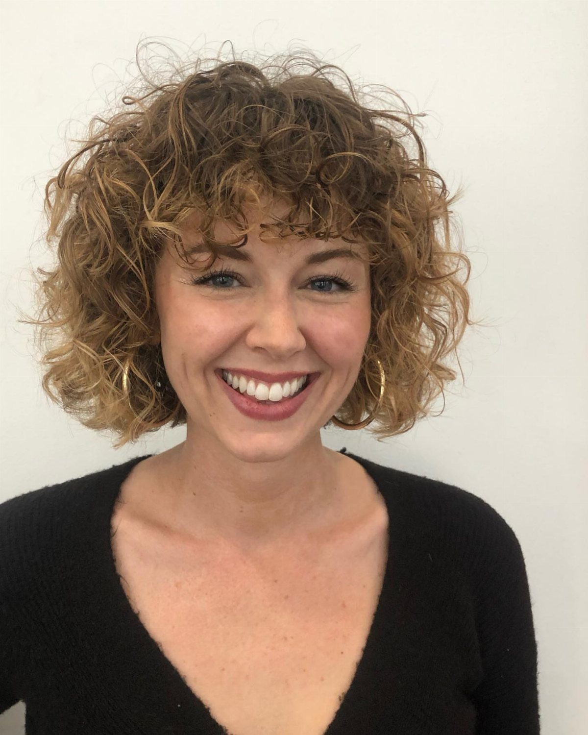 Woman with a short curly bob and forehead-framing bangs