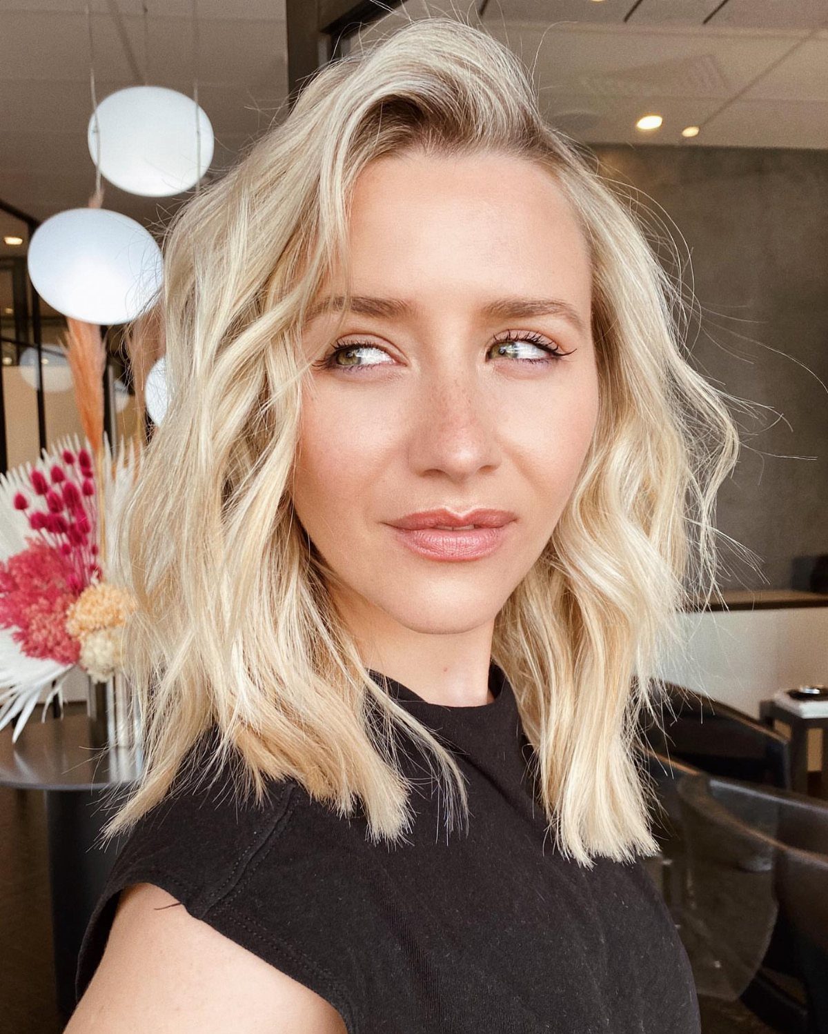 Woman with voluminous shoulder-length blonde waves and a side part in a salon