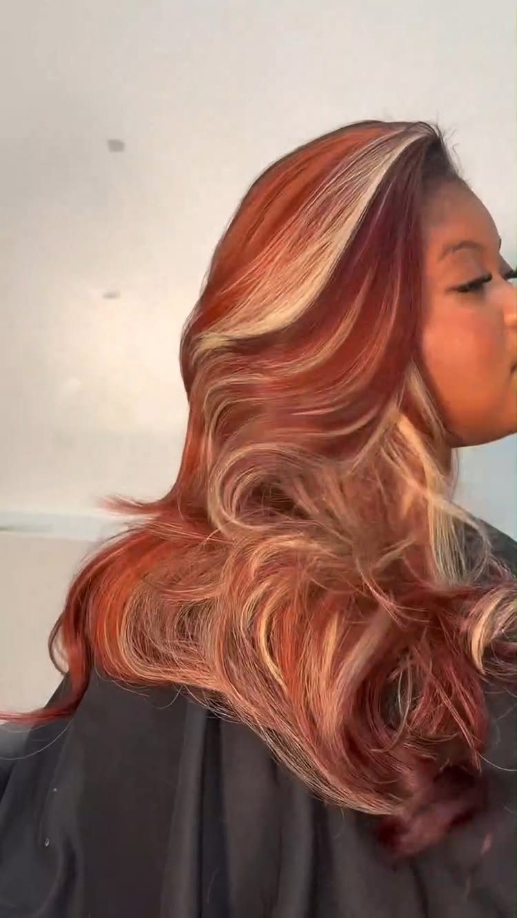 Woman with long wavy auburn blonde hair and sweeping copper highlights