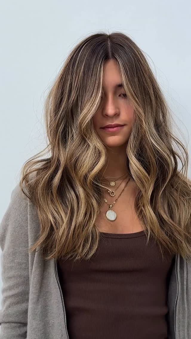 Woman with long wavy dark blonde hair and lighter beige highlights