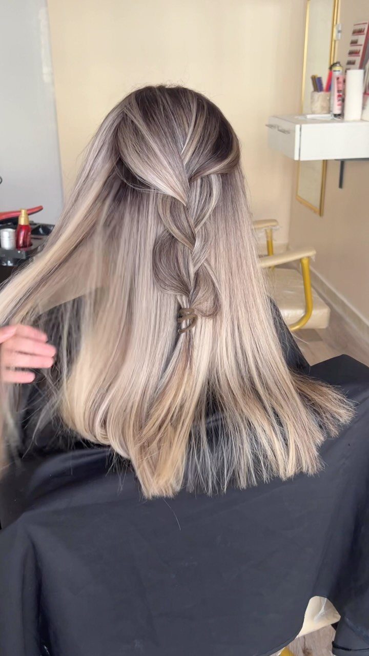 Long muted ash blonde hair with brunette tones styled in a partial braid